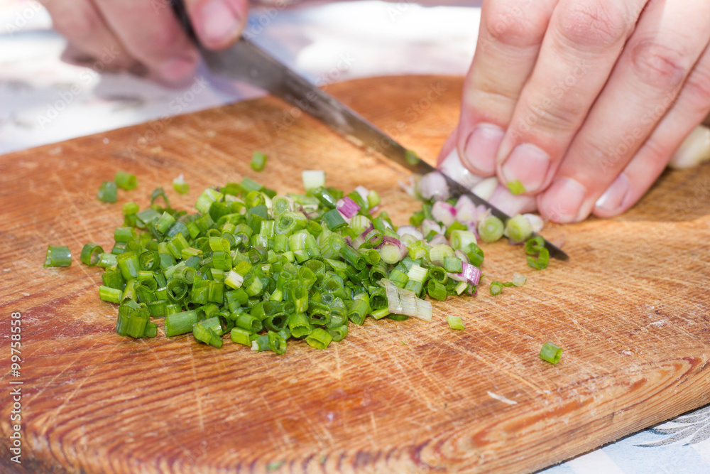 Cook chops onions for salad on a wooden board Cook chops onions for salad on a wooden board