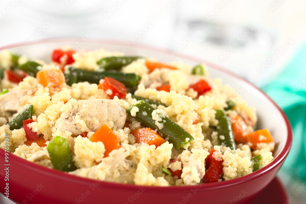 Couscous dish with chicken, green bean, carrot and red bell pepper served in a red bowl (Selective Focus, Focus one third into the dish) Couscous dish with chicken, green bean, carrot and red bell pepper served in a red bowl (Selective Focus, Focus one third into the dish)