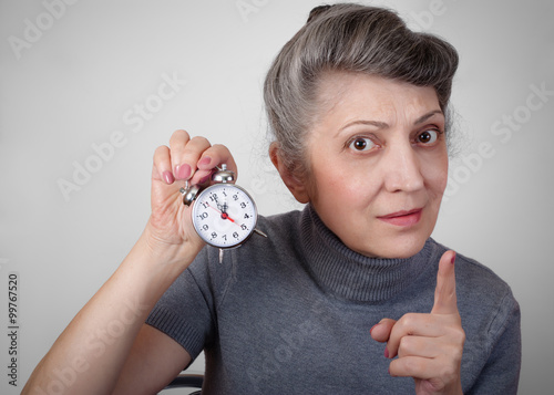 Portrait of an elderly woman holding a clock concept of time is running out