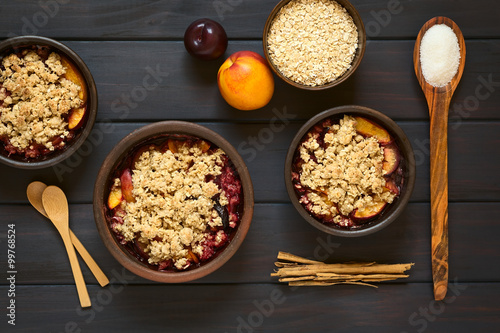 Принти на полотні Baked plum and nectarine crumble or crisp, photographed on dark wood with natura