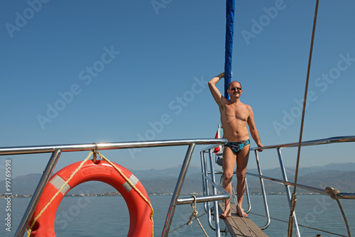 Mature man is on the pleasure yacht's bowsprit.