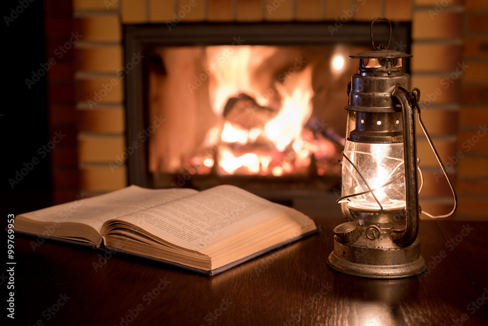Open book by the Fireplace with kerosene lamp. Stock Photo | Adobe Stock