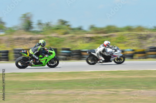 фотографія Blurred athletes practicing racing motorcycles on the race track
