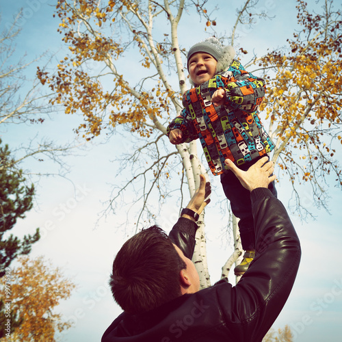 Happy father to tosses up his little son  park outdoor  image to