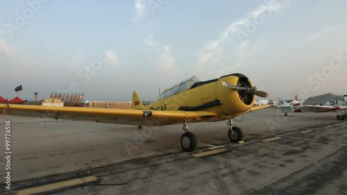 Pan across to a wide angle view of a T-6 Harvard (also known as a Texan) training aircraft, parked at airfield.  Recorded in 4K, ultra high definition.