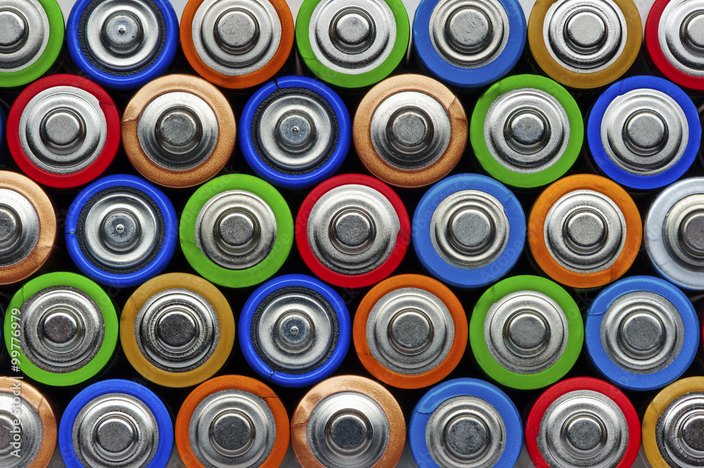 Batteries, top view, rows of alkaline battery AA size format in green, red, blue, bronze, gold, orange, colors, energy abstract background Batteries, top view, rows of alkaline battery AA size format in green, red, blue, bronze, gold, orange, colors, energy abstract background
