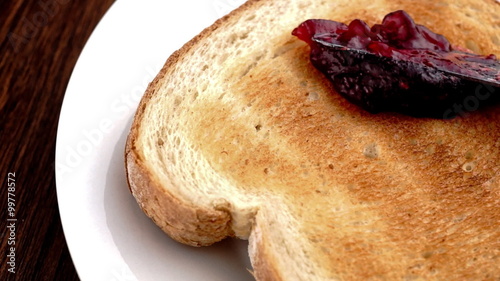 Strawberry raspberry jam being spread on toast in slow motion