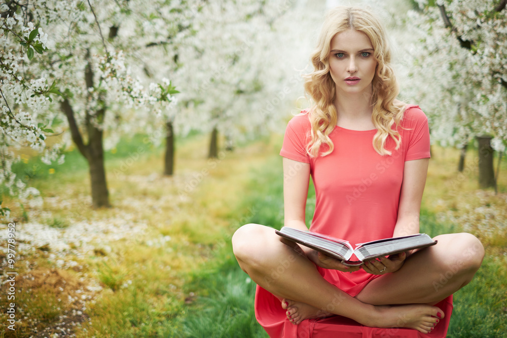 Obraz premium Conceptual image of blonde reading a book in orchard