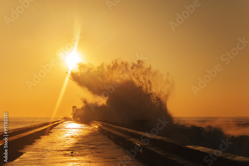Wave splash at sunset near lighthouse