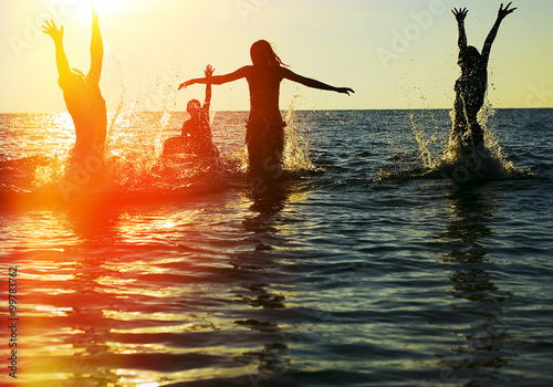 Silhouettes of people jumping in ocean