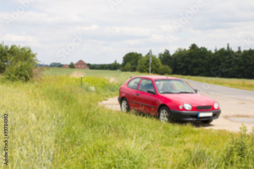 Blurred photo of car standing next to the meadow