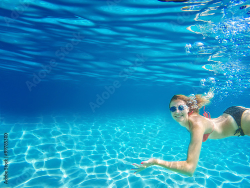 Female snorkeling underwater and looking at camera. Deep blue sea. Clear water.