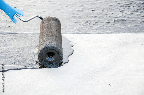 Roofer worker painting  bitumen praimer at concrete surface by t