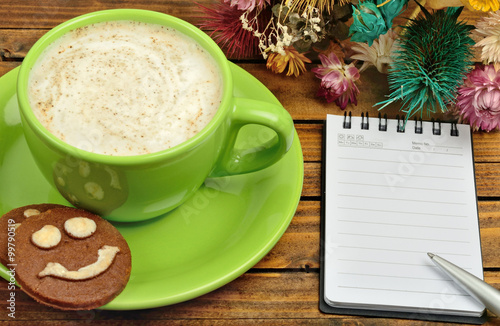 Cup of cappuccino with empty notebook
