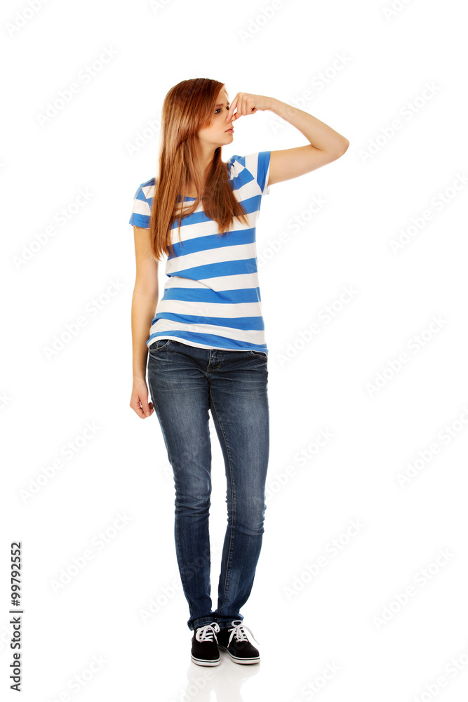 Teenage woman holding her nose because of a bad smell Teenage woman holding her nose because of a bad smell