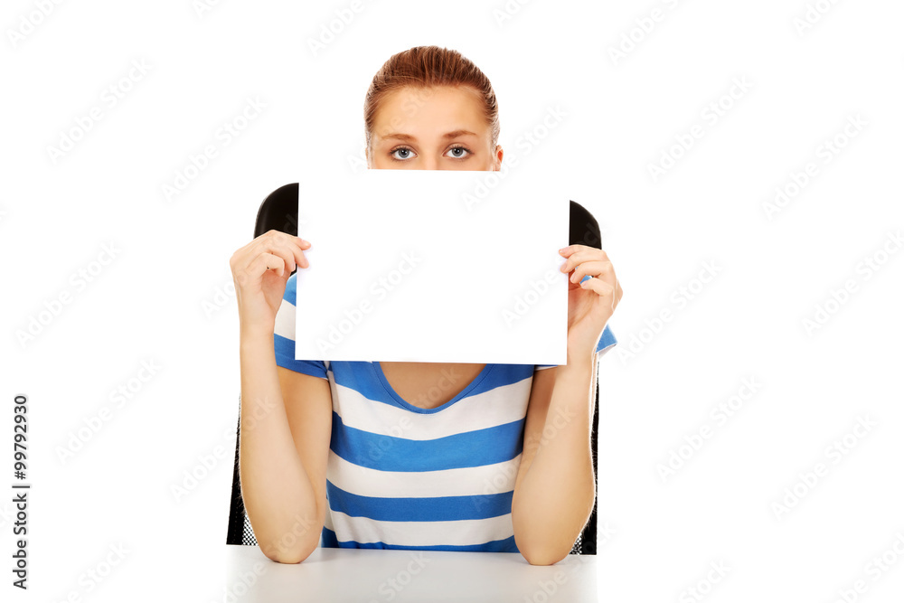 Teenage woman covering face with paper card