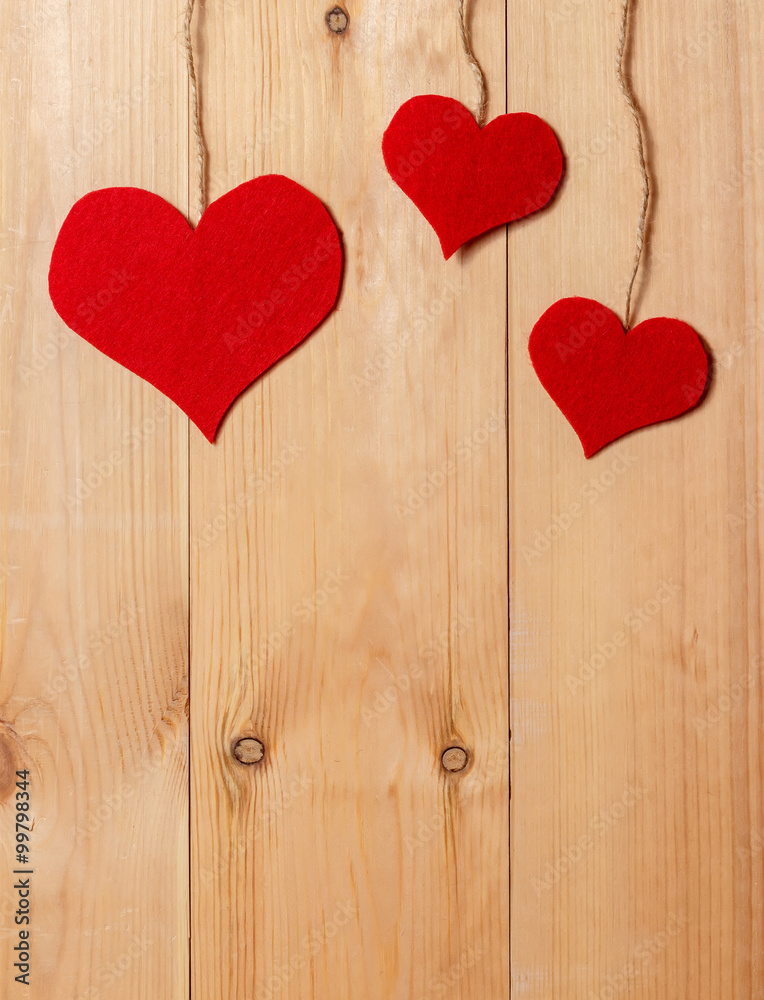Handmade hearts hanging on line against wood-grain wall Handmade hearts hanging on line against wood-grain wall