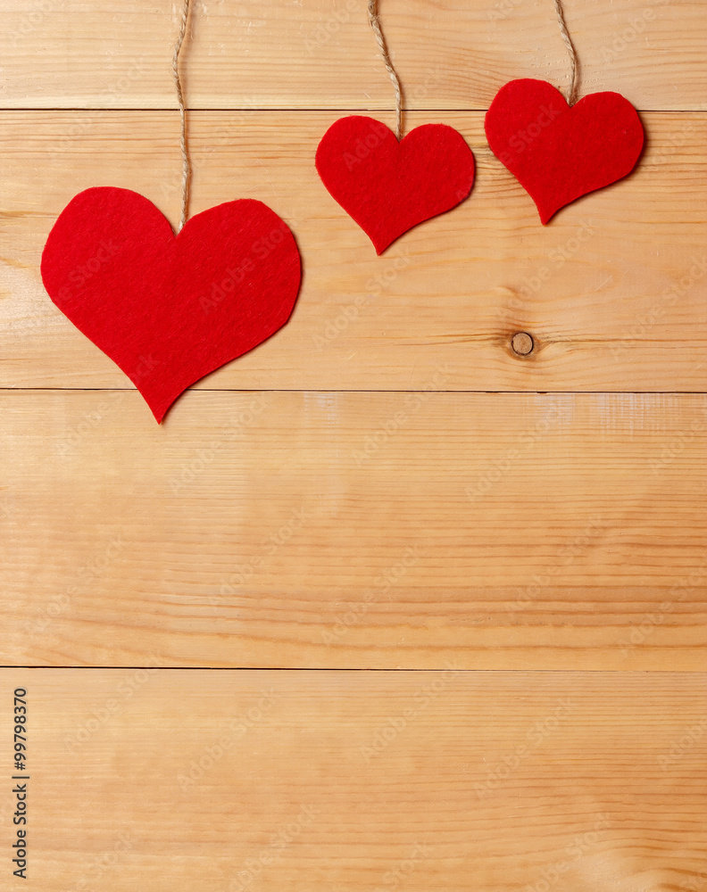 Handmade hearts hanging on line against wood-grain wall Handmade hearts hanging on line against wood-grain wall
