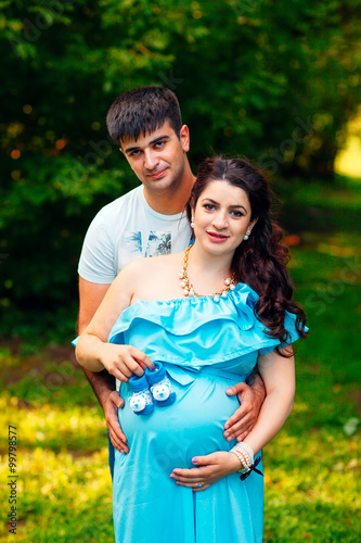 Beautiful pregnant couple relaxing outside in the park.