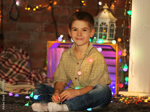 Little boy in light garland at home on a Christmas background © Africa Studio