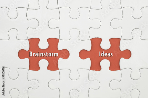 Jigsaw puzzle on color paper background with a word Brainstorm and Ideas
