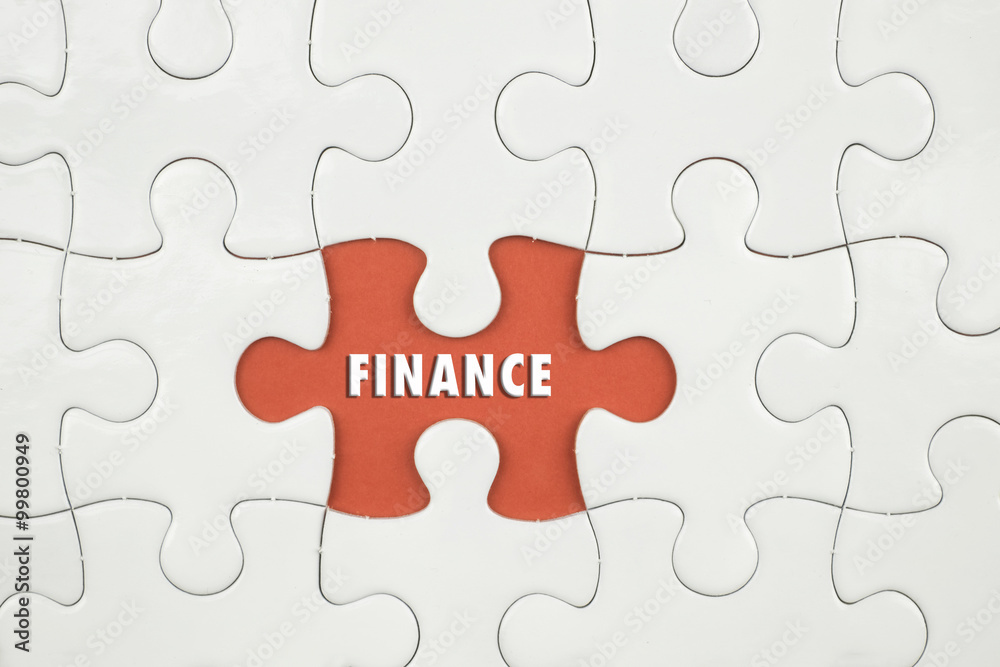 Jigsaw puzzle on color paper background with a word FINANCE Jigsaw puzzle on color paper background with a word FINANCE