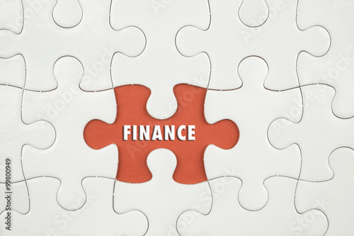 Jigsaw puzzle on color paper background with a word FINANCE