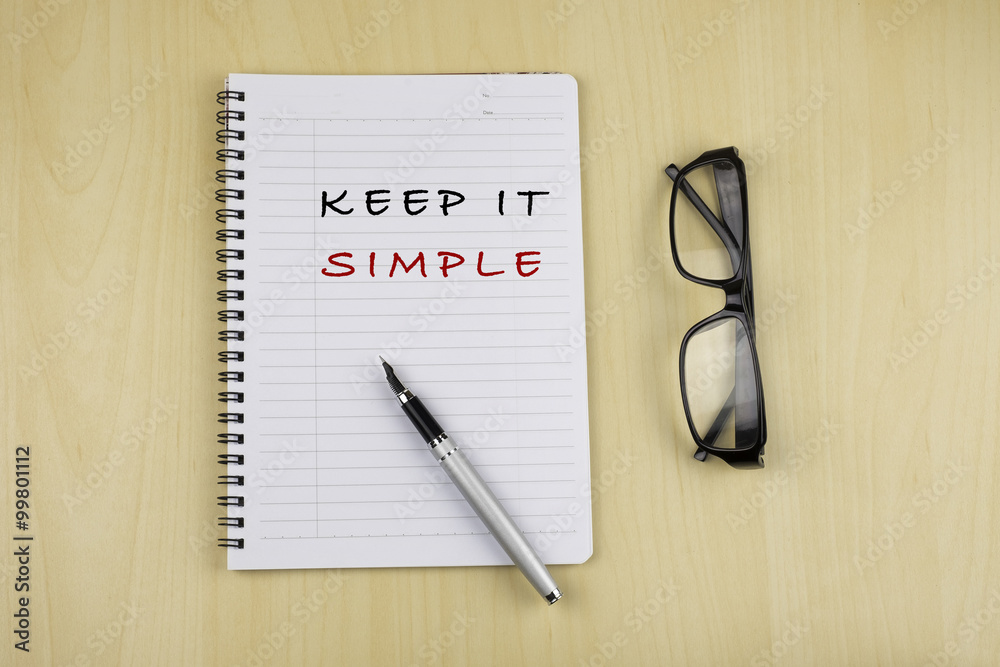 The words Keep it Simple written on a white notepad with glassess The words Keep it Simple written on a white notepad with glassess