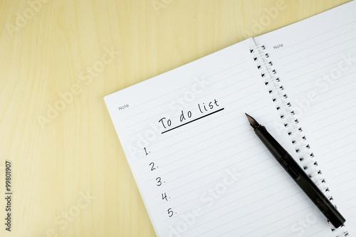 "To do list" is written on notepad with pen on office table. Top View