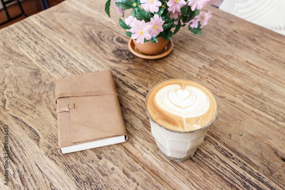 Cup of coffee latte art with leather notebook on wood table Cup of coffee latte art with leather notebook on wood table