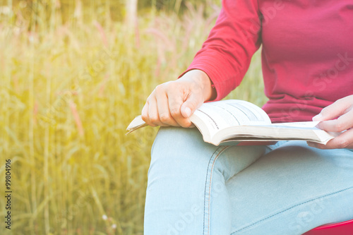 Girl laying on a book on his leg, Nature scene blurred