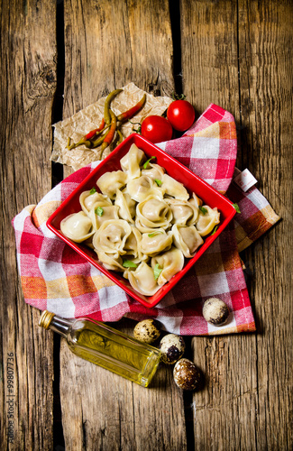 Homemade ravioli is prepared in a cup. On wooden background. photo