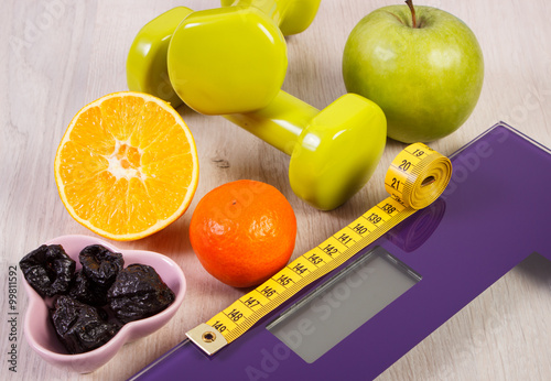 Digital scale with tape measure, dumbbells, fruits, slimming concept