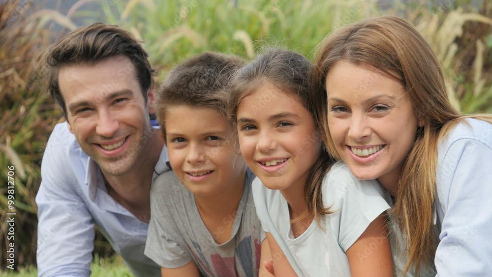 Portrait of happy family of four laying in grass Portrait of happy family of four laying in grass