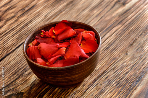 Rose petals in a bowl on a wooden background