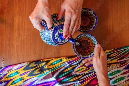 Pouring black tea from teapot in bowl in uzbek restaurant