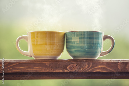Fototapeta Naklejka Na Ścianę i Meble -  Mugs with a hot drink with tea on a wooden stand outdoors