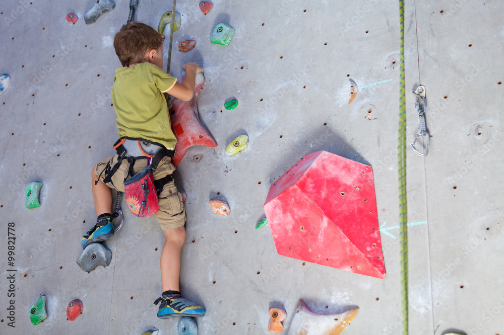 little boy climbing a rock wall