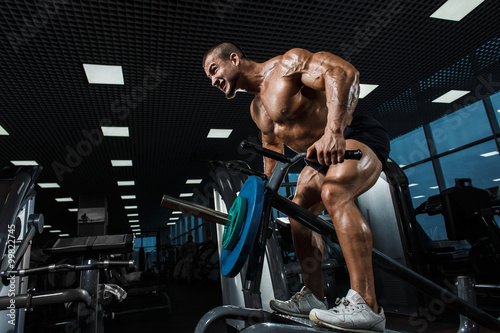 Athlete muscular bodybuilder in the gym training back with T-bar