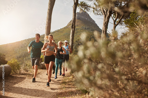 Group of fit people trail running on a mountain path