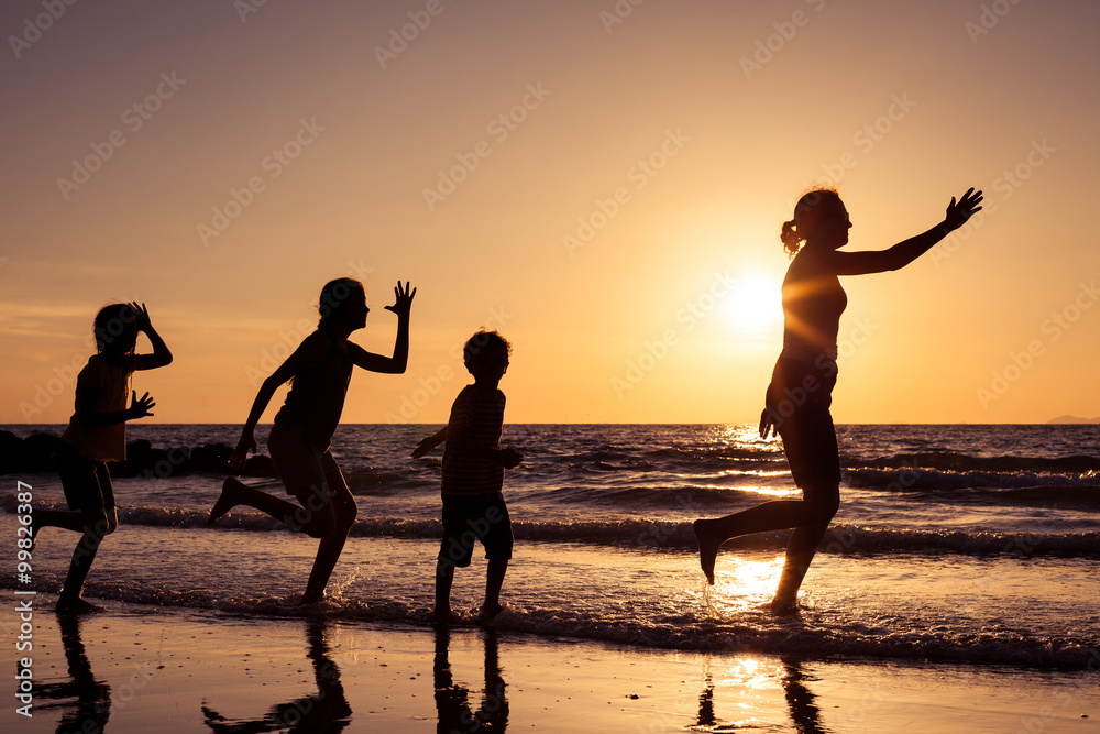 Fototapeta premium Mother and children playing on the beach at the sunset time.