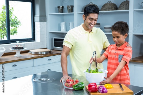 Smiling father preparing salad with his son