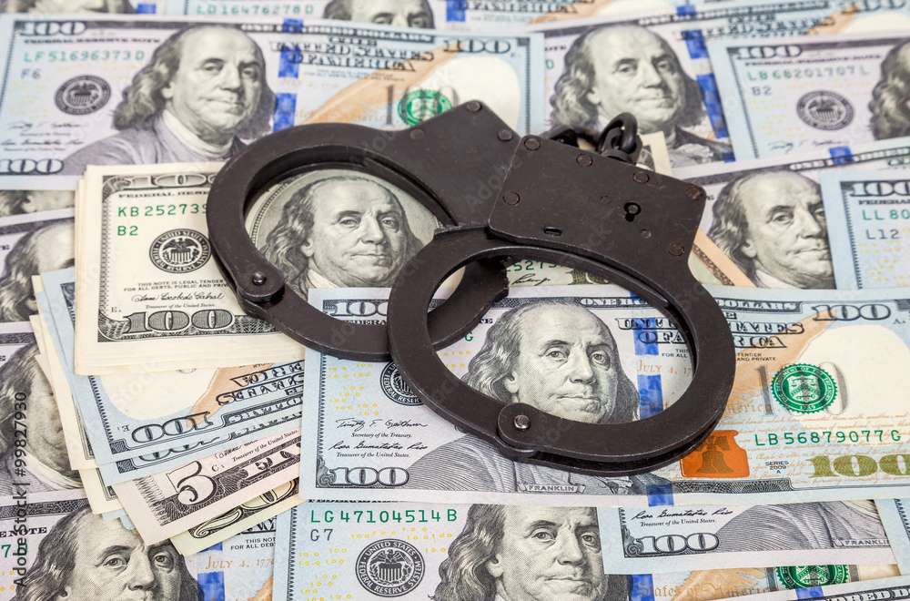 Steel handcuffs lying on the american dollar bills Steel handcuffs lying on the american dollar bills