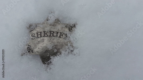 Snow falling on sheriff badge. photo