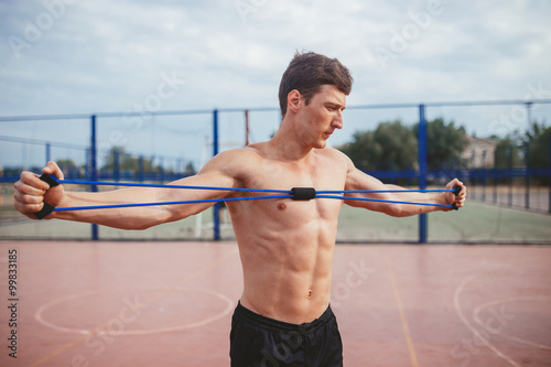 strong athletic guy sports man stretches expander