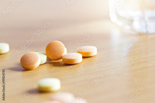 Pills and water in glass on wooden background, warm color tone