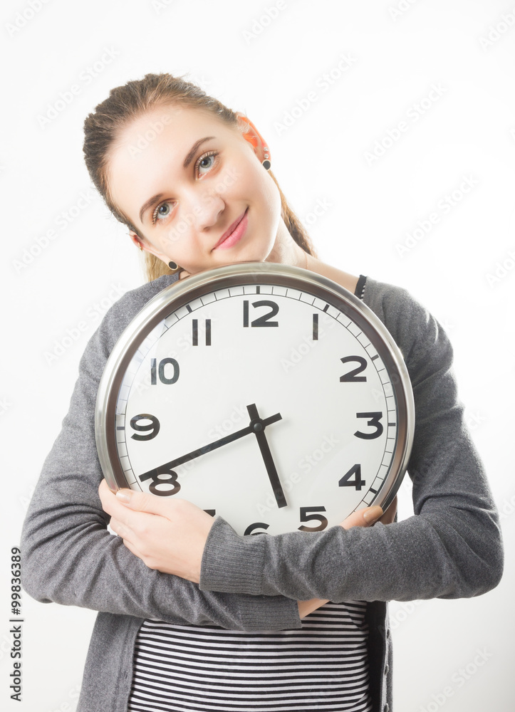 Beautiful young woman looking at a large silver retro clock that she is holding, she wonders how much time passed Beautiful young woman looking at a large silver retro clock that she is holding, she wonders how much time passed