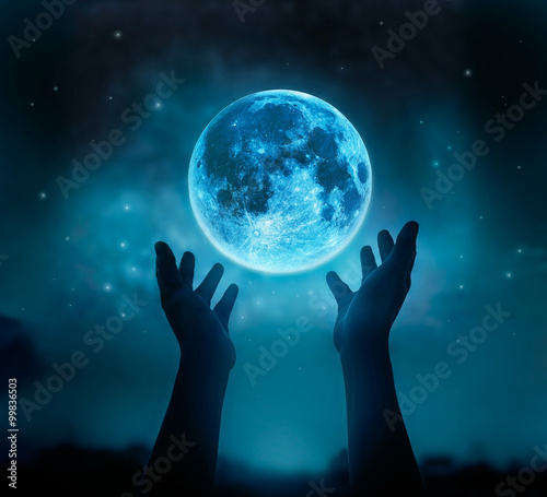 Foto Abstract hands while praying at blue full moon with star in dark background