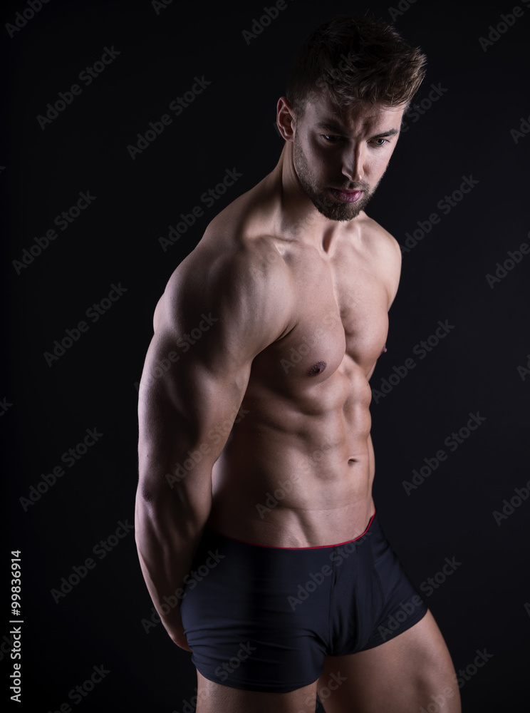 handsome young bodybuilder with toned body posing shirtless