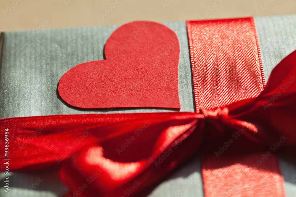 Fototapeta premium Valentine gift box wrapped in silver paper, with red bond and re